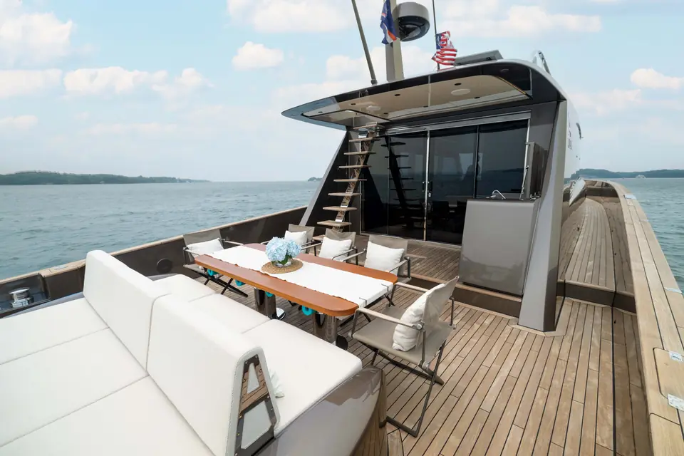The aft deck: transom sofa across the full beam, table set, open on three sides to the water.