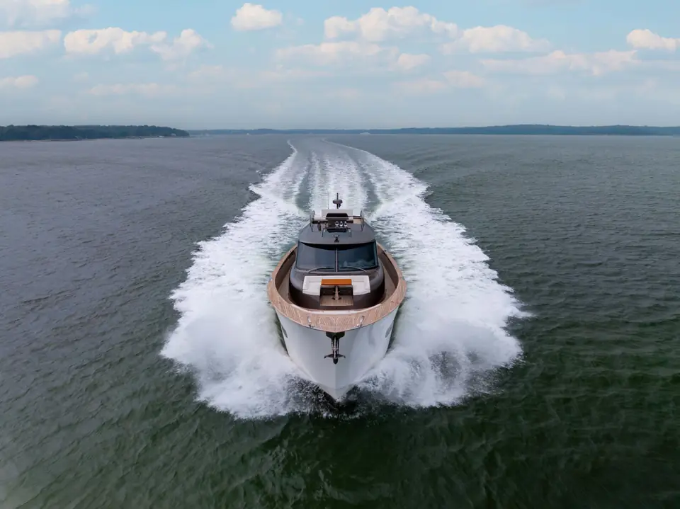 HIDEOUT bow-on at speed, spray thrown either side, wake running straight to the horizon.