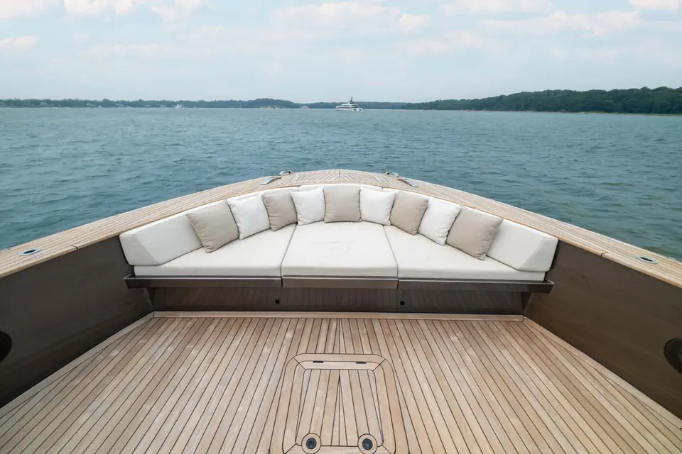The bow settee at anchor, cushions laid, anchor chain running out over the stem.