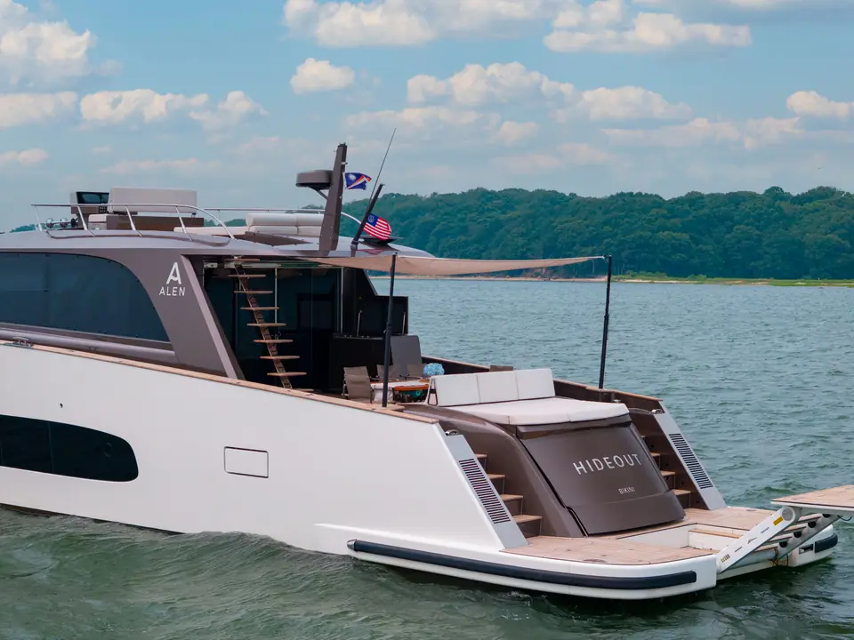 The transom: teak swim platform down to the water, garage hatch closed, boarding gates either side.