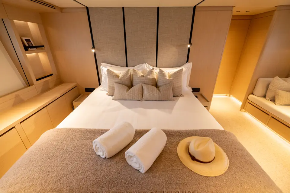 The master cabin: full-beam berth, hull windows either side, joinery kept below the window line.