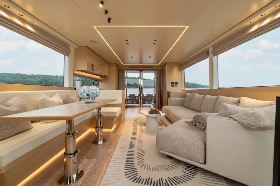 Main salon on the centerline: dinette to port, sofa to starboard, glazed doors open onto the aft deck.