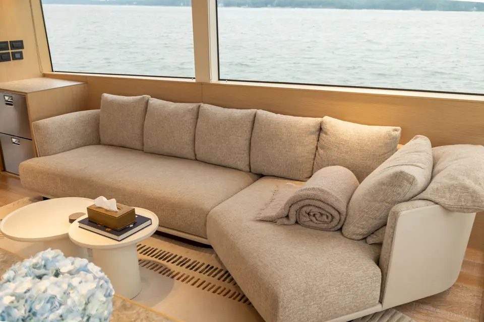 The salon sofa set below the window line, sea running past outside at eye level.