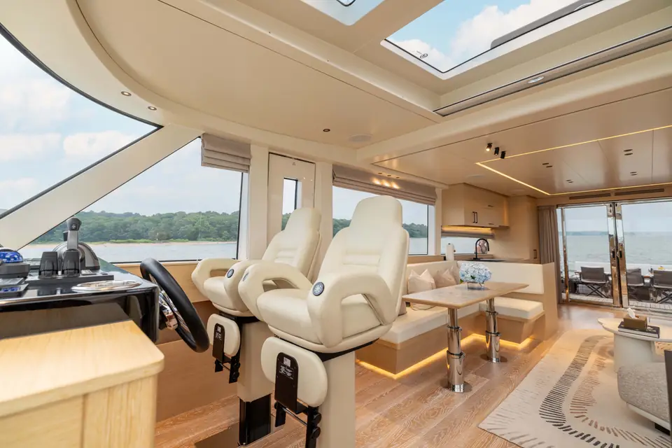 The main deck salon looking aft: dinette to port, sofa to starboard, glazed doors open to the cockpit.